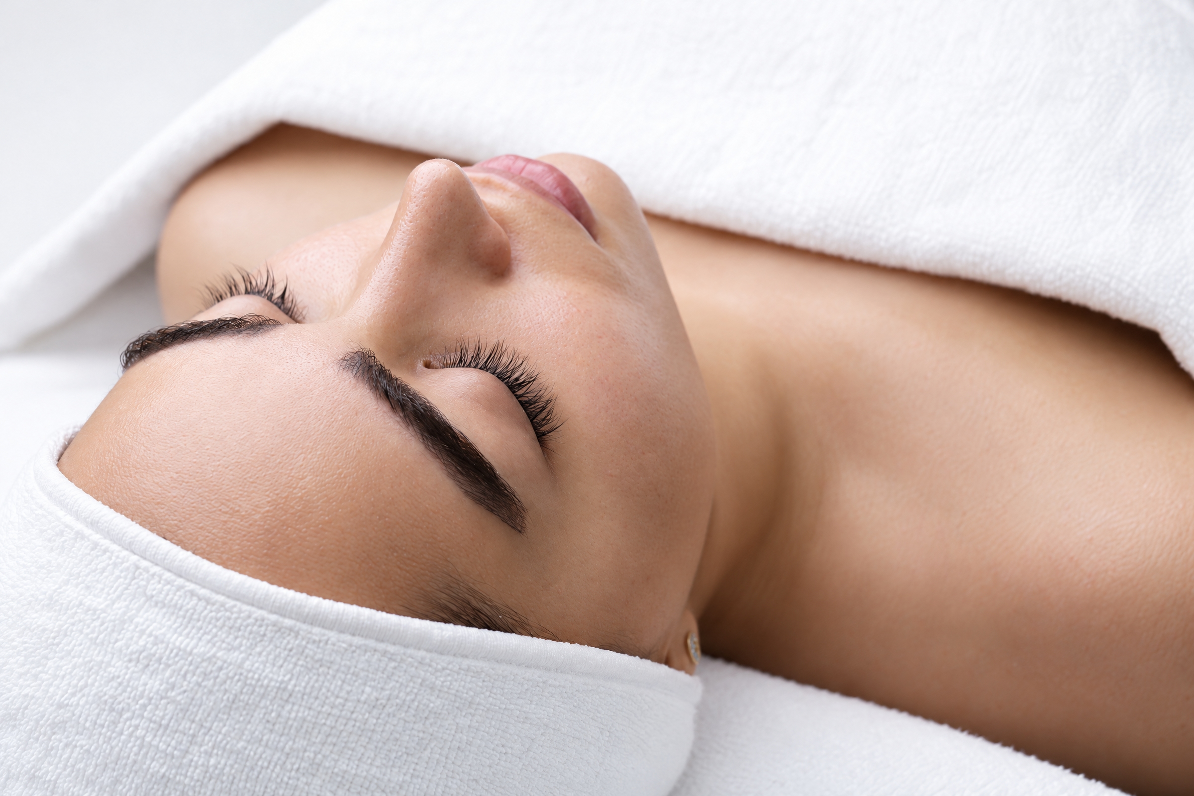 A relaxed woman resting with her eyes closed during a facial